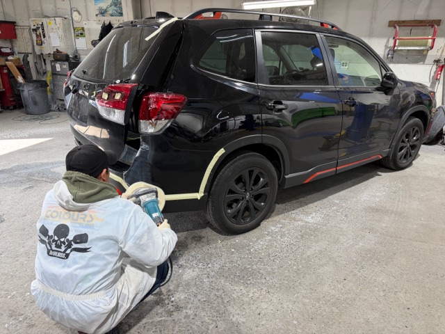 Mizzoni's technician performing professional paint buffing and finishing on a black Subaru Forester in the Lodi NJ shop